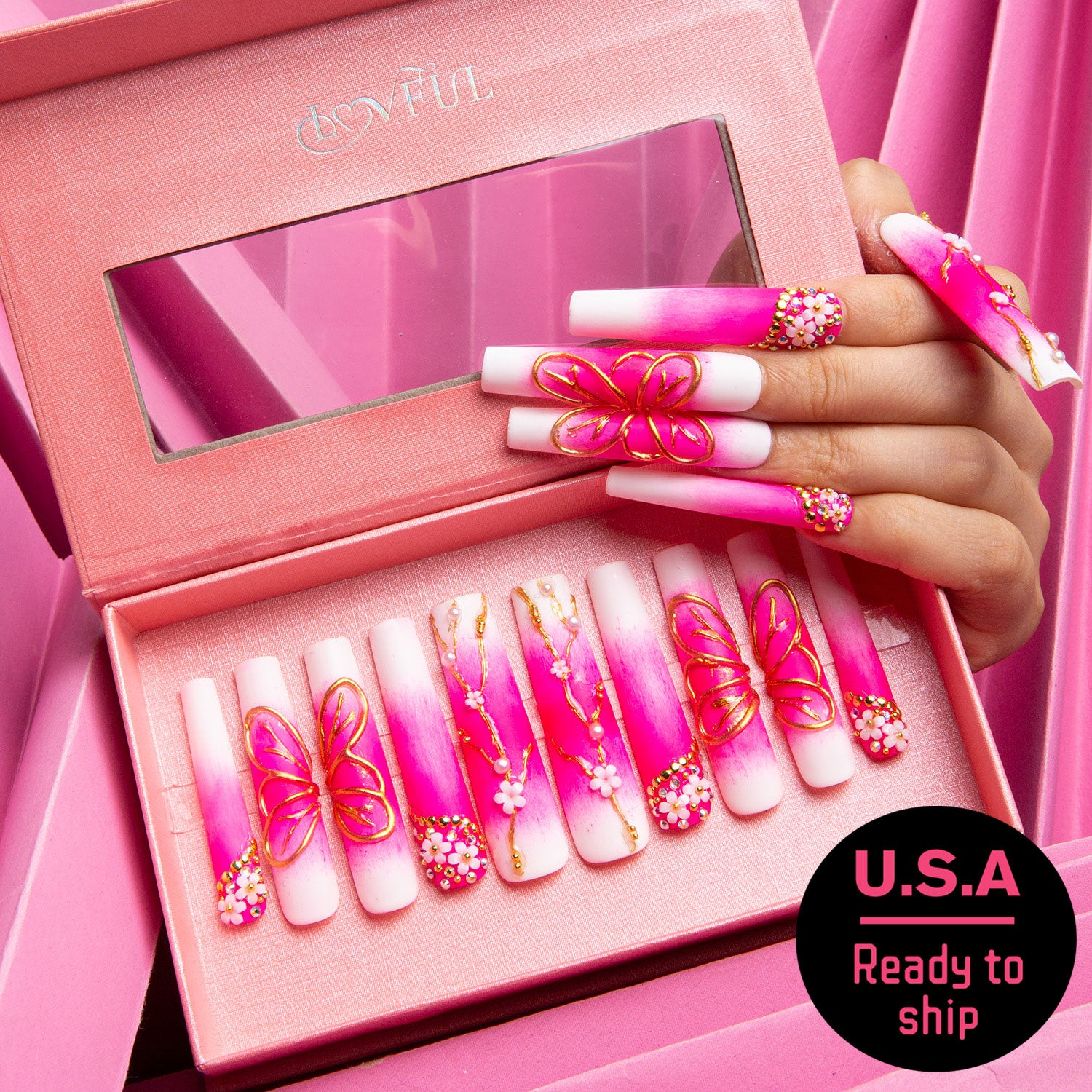 Press-on acrylic nails set in a pink box with mirror, featuring pink and white gradient design with butterfly and cherry blossom decorations. Label reads 'U.S.A Ready to ship'.