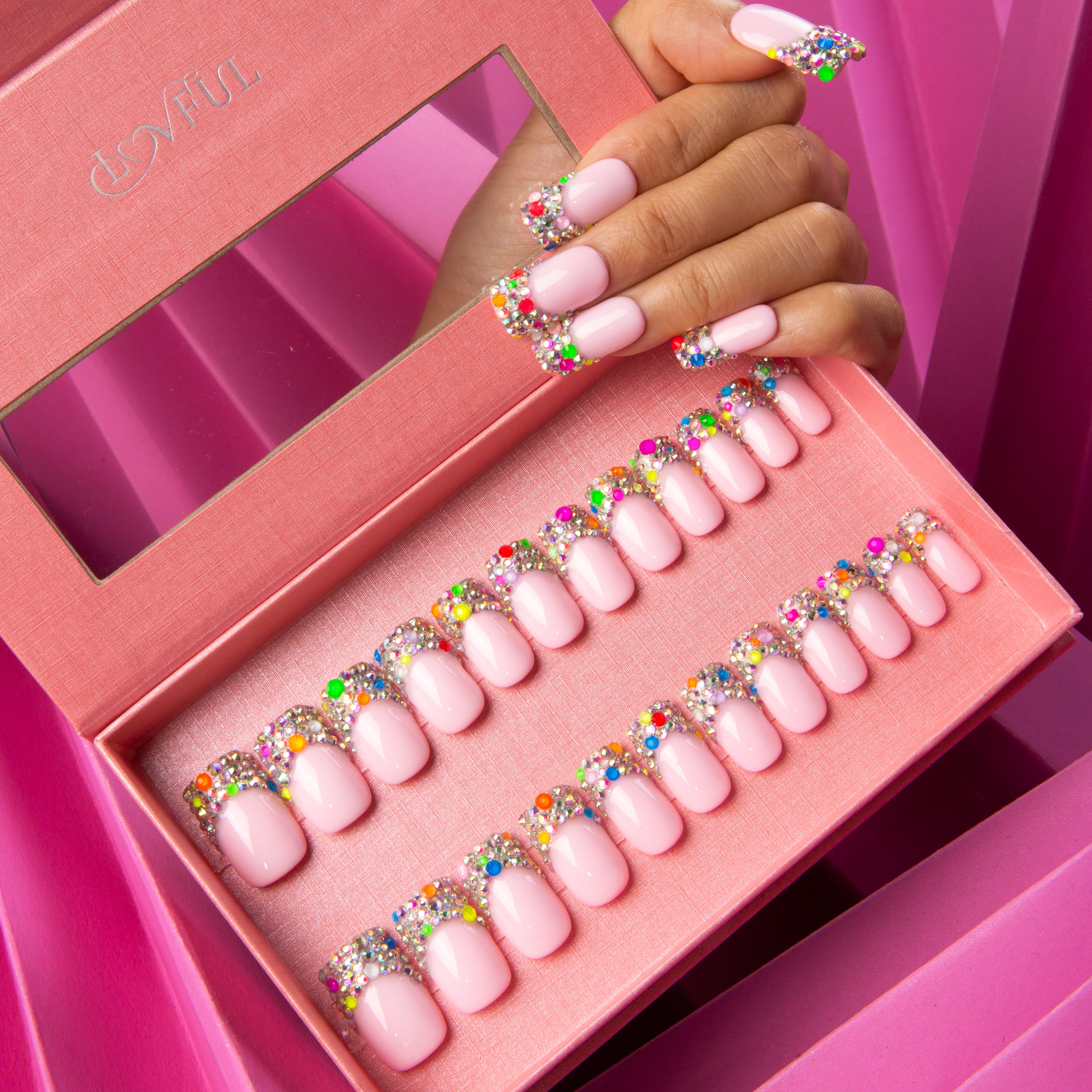 Hand displaying Jelly Bean press-on nails with colorful tips, holding an open pink box containing 24 similar press-on nails from Lovful.com