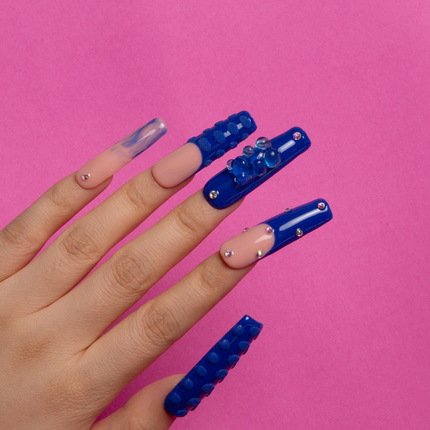 Hand with Little Blue Bear Rhinestone French tip press-on nails featuring blue hue with gummy bears, rhinestones, and 3D dots.