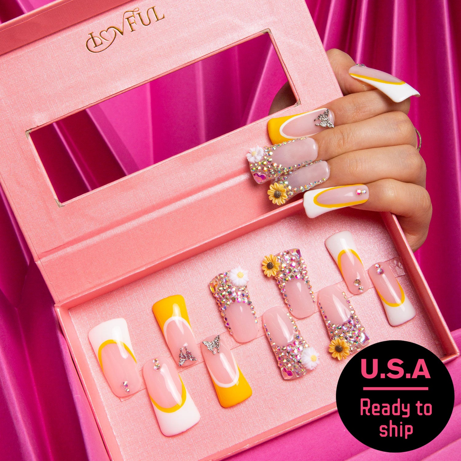 Sunflower press-on nails set with yellow hues, French tips, sunflower designs, and jewel embellishments displayed in a pink Lovful box. A hand showcasing the nails and a 'U.S.A. Ready to ship' label.