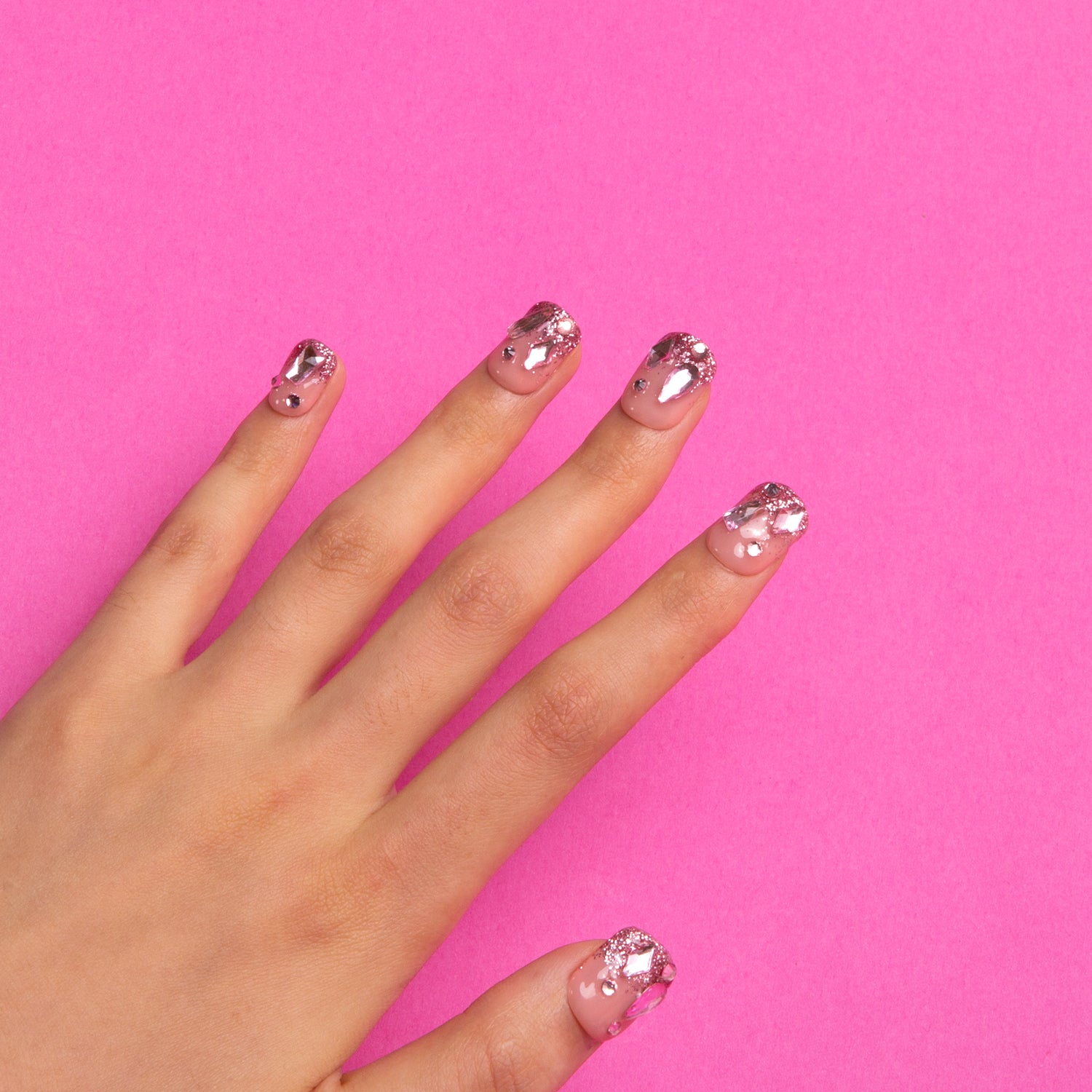 Pink glitter square press on nails with rhinestones on pink background