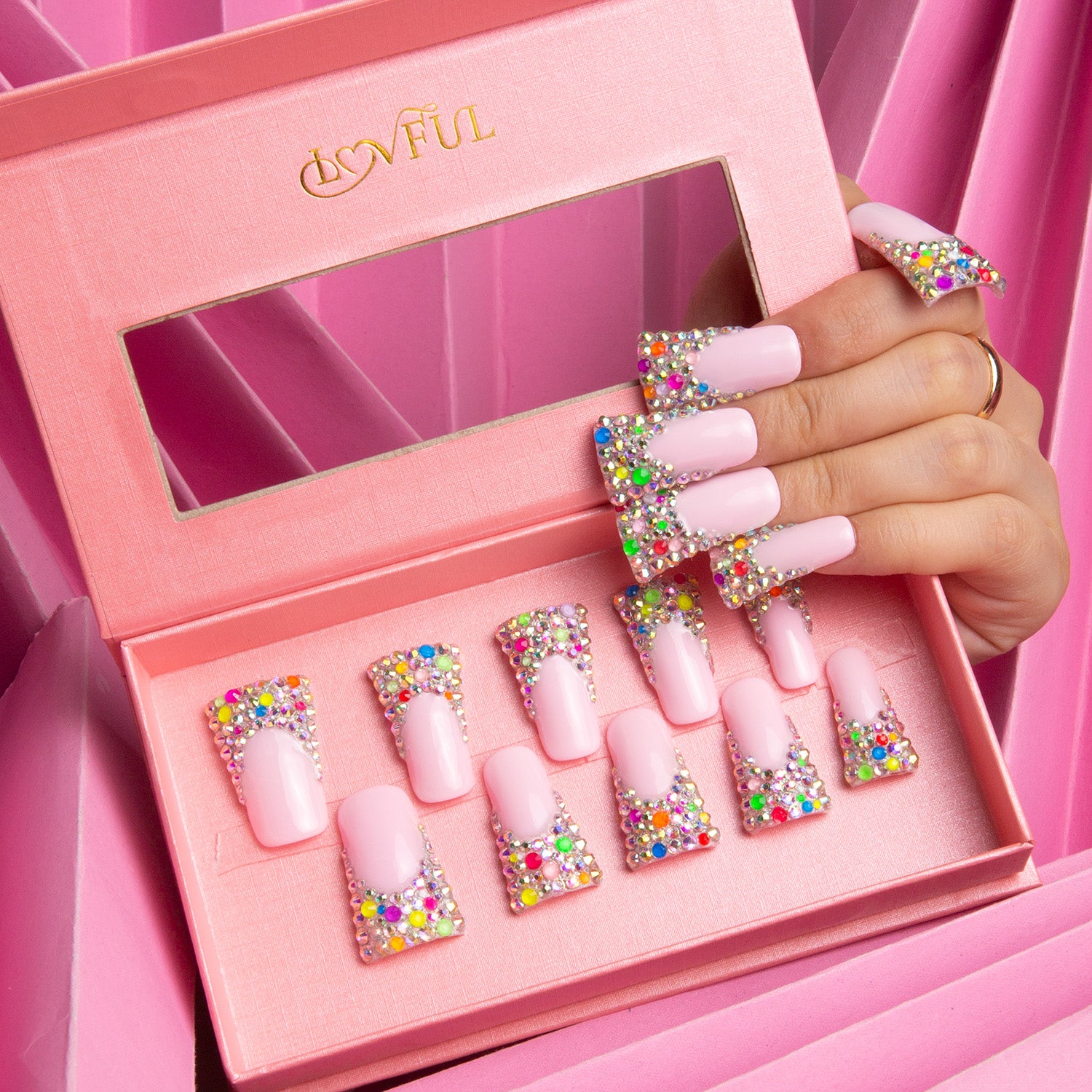 Lovful 'Jelly Bean' press-on nails set in an open pink box, featuring a nude base with colorful, sugary beads on the tips. A hand displays the nails applied, highlighting the playful and whimsical design.