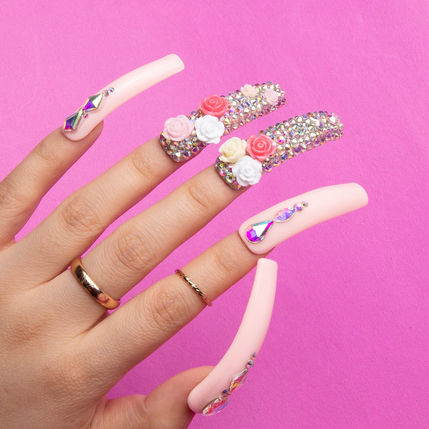 Hand showcasing Lovful's Rose Garden Bliss press-on nails featuring detailed roses and shimmering rhinestones on light pink curved acrylic nails.