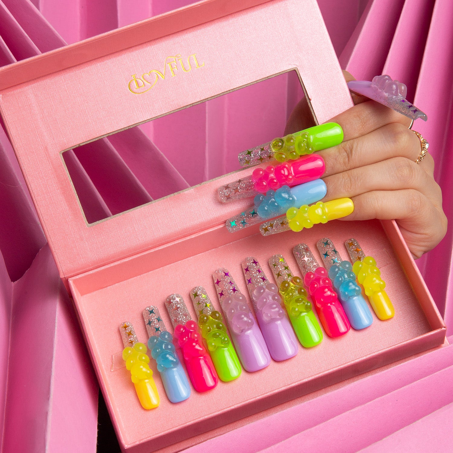 Lovful Sweet Wonderland press-on nails set with vibrant colors and glowing gummy bear charms in a pink box. Hand showcasing applied nails.