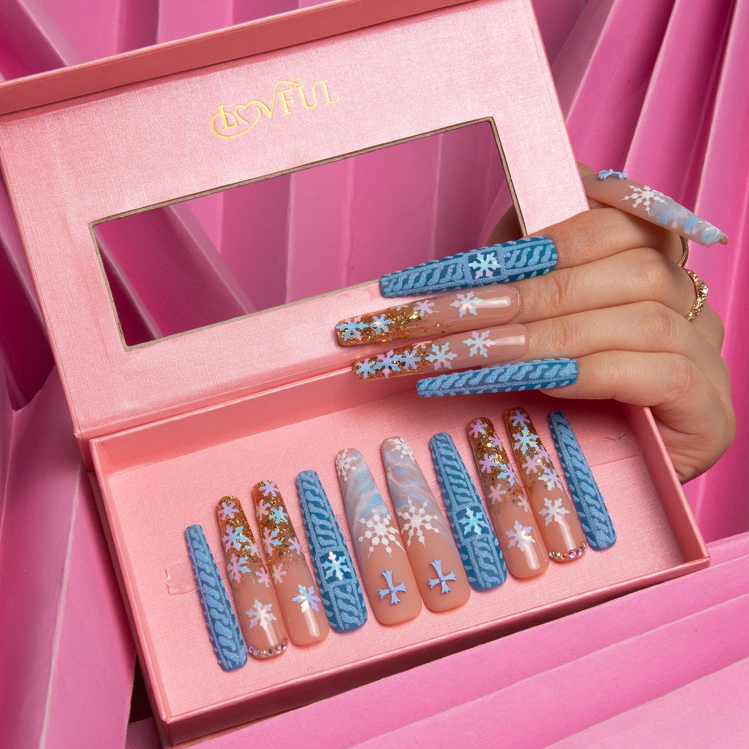 Lovful 'Winter Sunshine' press-on nails in coffin shape featuring soft blue color with golden glitter and snowflake patterns, displayed in an open pink box against a pink background.