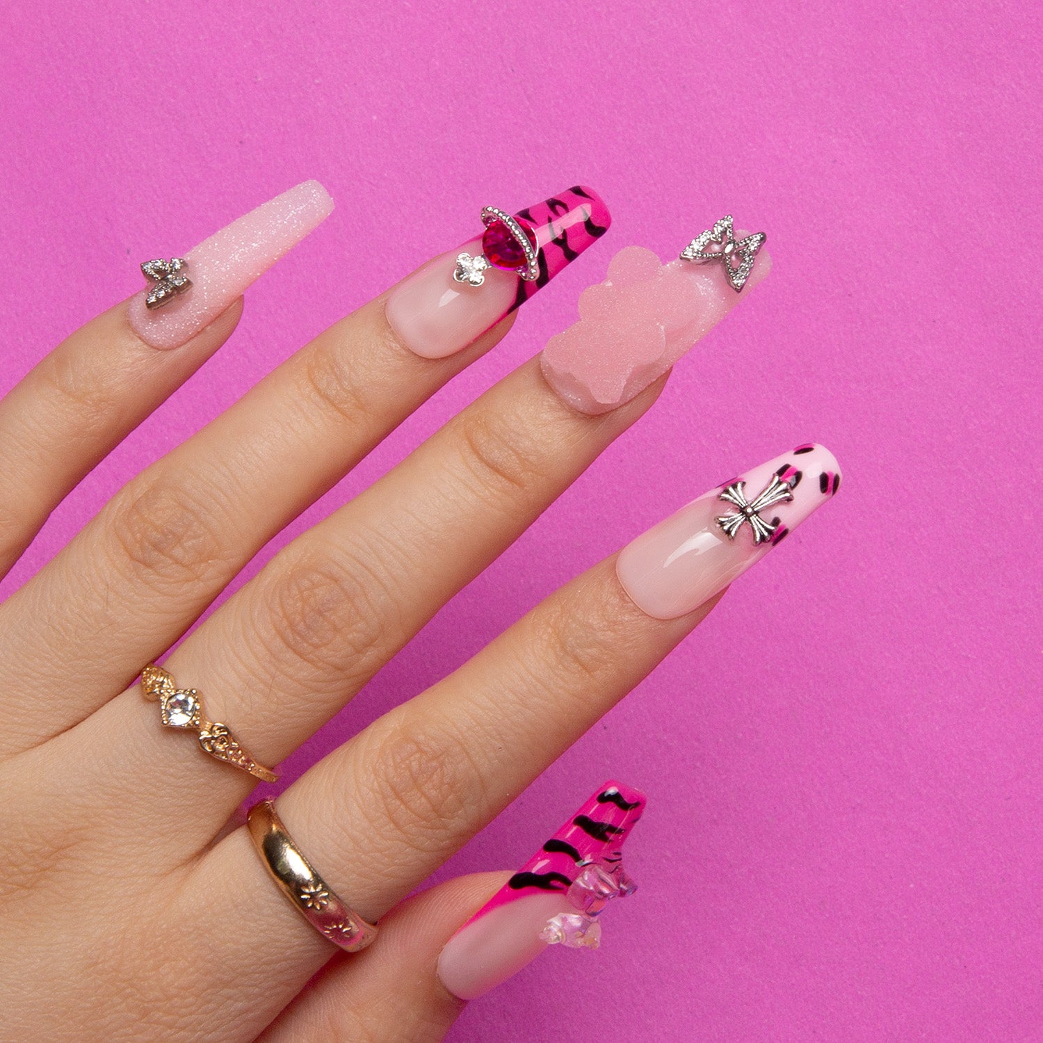 Hand showcasing 'Safari Love' press-on nails by Lovful.com with hot pink French tips and hand-drawn leopard prints, accented with lips, bows, and butterflies on a pink background.