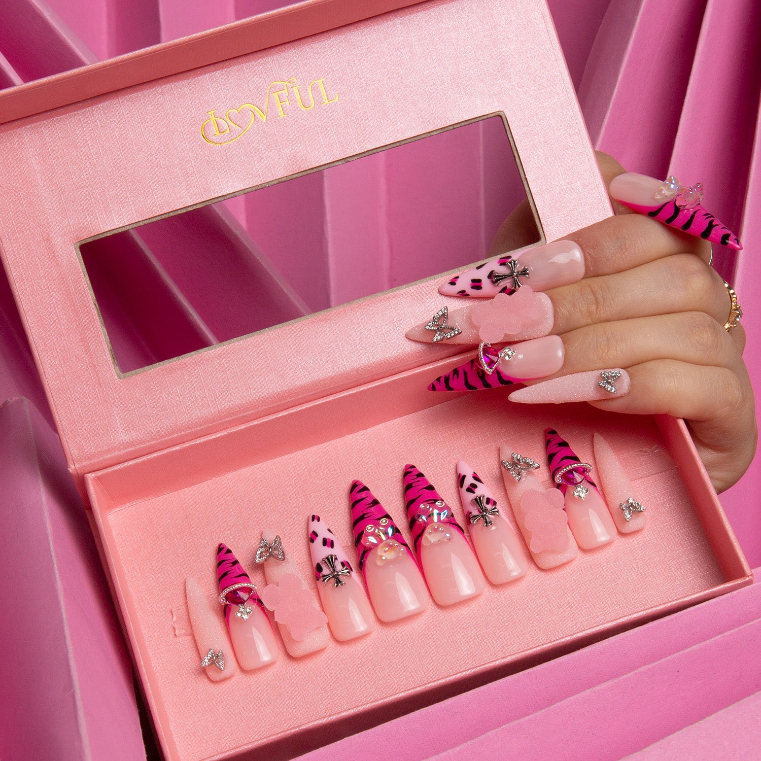 Lovful 'Safari Love' press-on nails with hot pink French tips, leopard prints, butterfly accents, and additional embellishments, displayed in a pink box with a clear window.