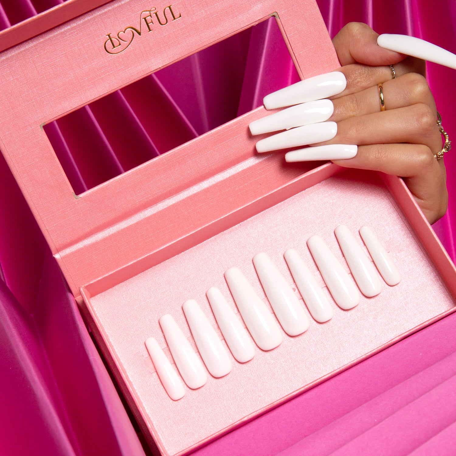 Luxurious white coffin-shaped press-on nails displayed in an open Lovful pink box with reflective mirror and organized nail sizes against a pink backdrop.