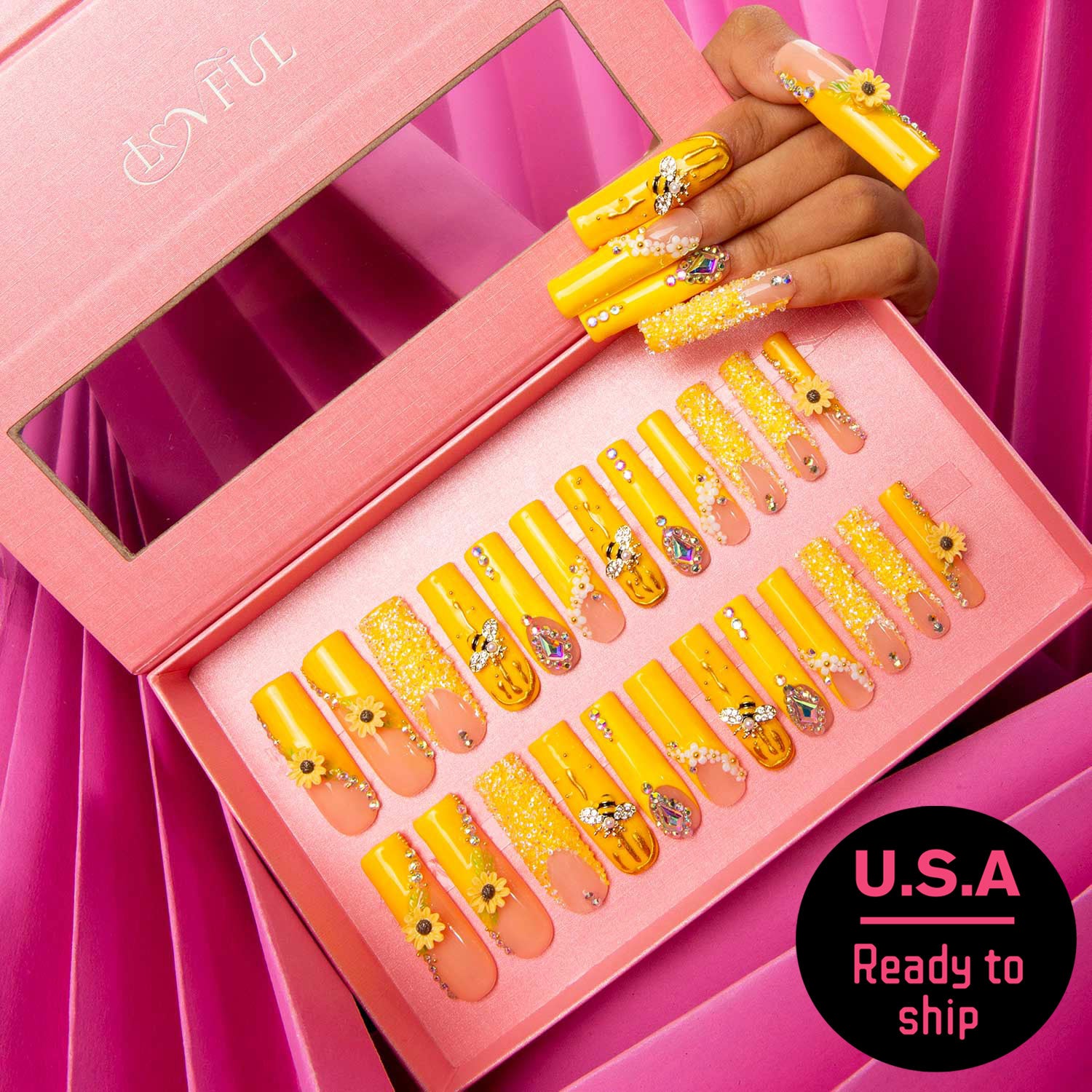 Bright yellow press-on nails with sunflower patterns and bee accents in a pink box, hand showcasing nails above, Lovful logo, U.S.A Ready to ship