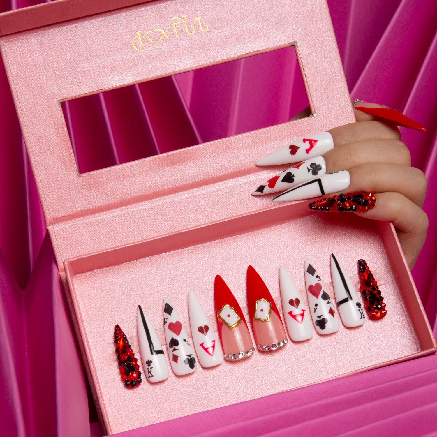 Lovful.com 'Poker Queen' stiletto press-on nails set in a pink box against a pink background. The nails feature red and white playing card designs, including hearts, spades, clubs, and diamonds, inspired by the Queen of Hearts from Alice in Wonderland.