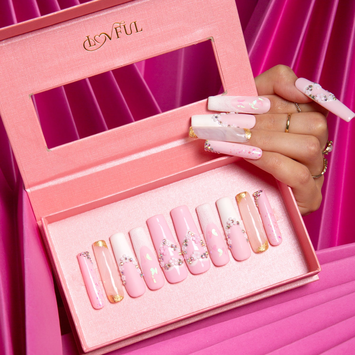 Lovful press-on acrylic nails set in light pink with French tips and heart-shaped flower designs in an elegant pink box. Ideal for bridal wear.
