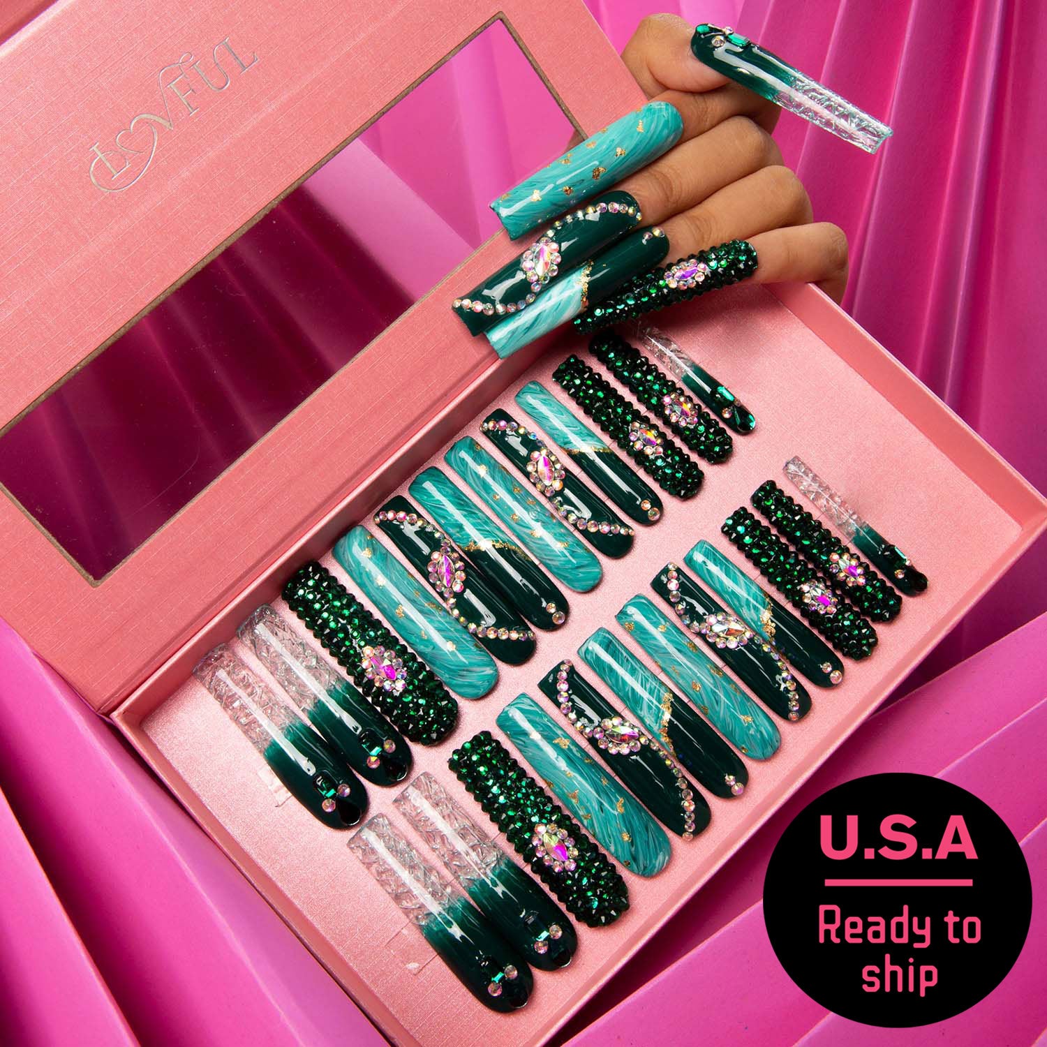 Lovful Emerald Envy Press-On Nails Set displayed in a pink box with 24 pieces, featuring intricate emerald green and gold designs, with a hand model showing some nails. U.S.A Ready to ship sticker on the bottom right.