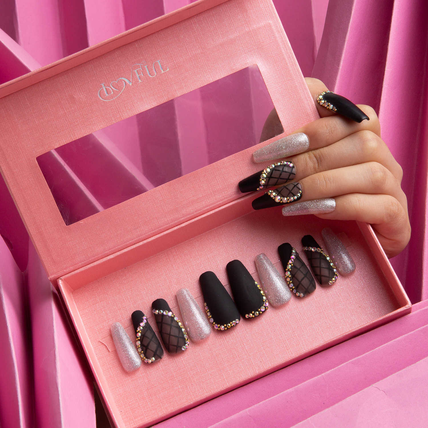 Hand displaying Lovful's Black Lace Coffin press-on nails with lace patterns and rhinestone accents, beside a pink Lovful branded nail box.