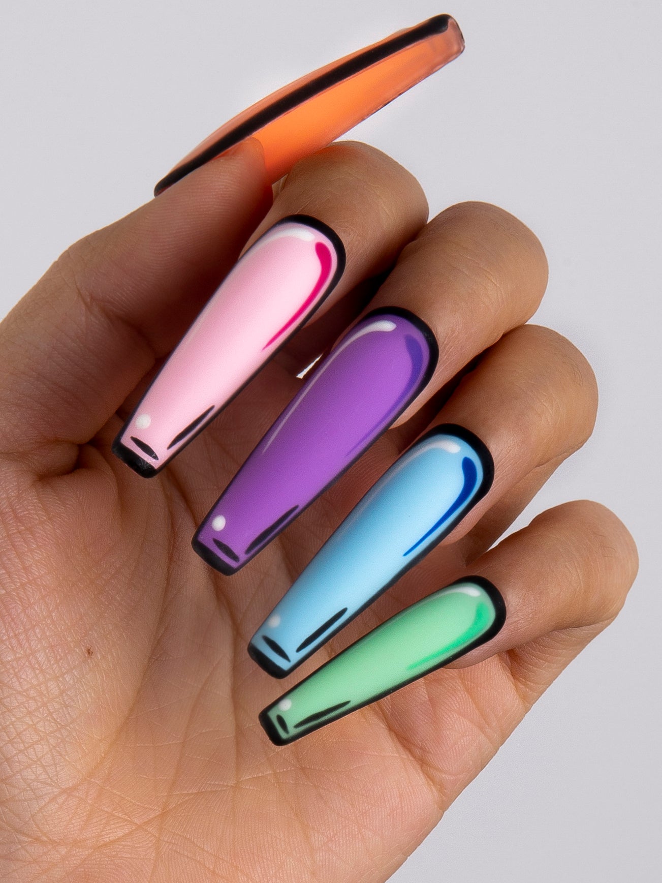 Hand with 'Colorful Pop' press-on nails featuring a bold pop art design in pink, purple, blue, green, and orange colors with black outlines. 24-piece set for a vibrant and artistic flair.