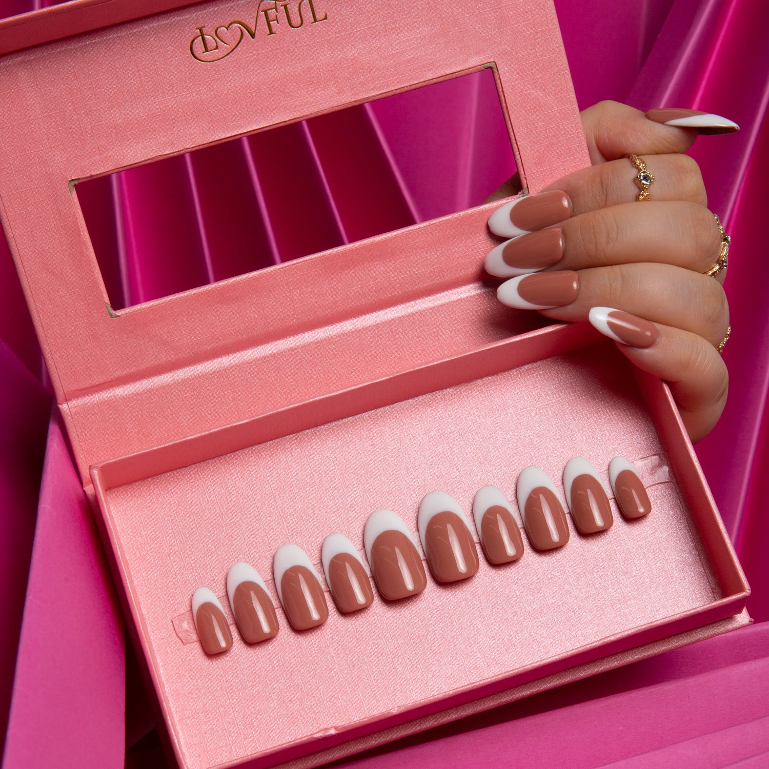 Hand displaying Coffee Latte French Tip press-on nails in a pink Lovful box, showcasing latte-colored nails with white French tips. Nail set is elegantly arranged in the box.