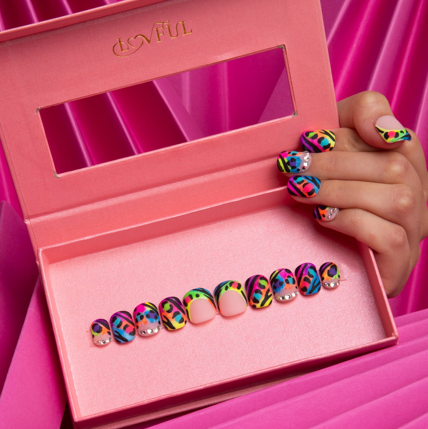 Hand holding a pink box displaying square-shaped press-on nails with colorful bright French tips and striking leopard prints from Lovful's H123 collection.