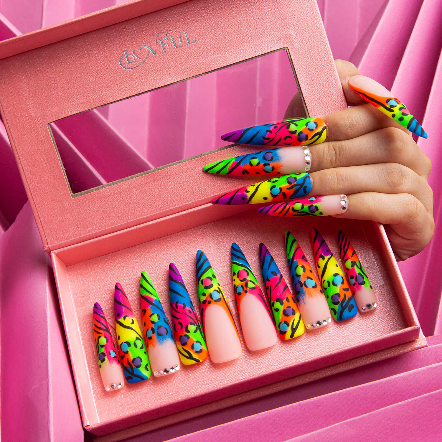 Set of colorful press-on acrylic nails with bright French tips and leopard prints in a pink box with Lovful logo, hand model showcasing some nails.