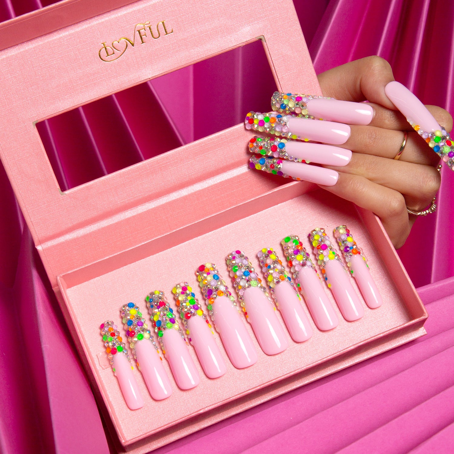 Lovful 'Jelly Bean' Press-On Nails in a pink box, featuring nude base with colorful beans on the tips, and a hand showcasing the same design, set against a pink satin background.