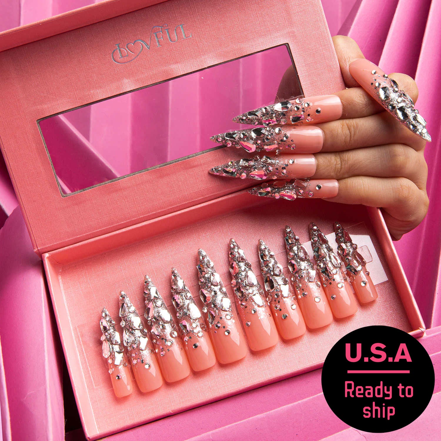 Hand showcasing long stiletto-shaped press-on nails with silver glitter and rhinestones, displayed in a pink Lovful branded box. U.S.A Ready to ship badge in the corner.