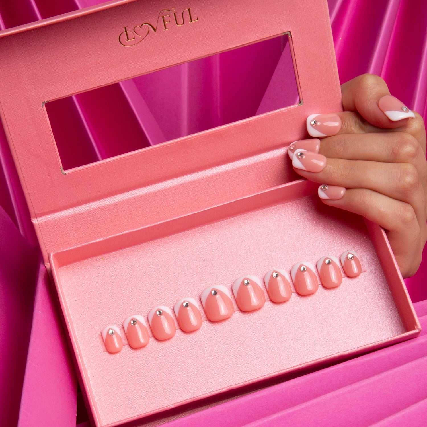 Eternal Polaris press-on nails with white triangle French tips and rhinestones from Lovful, displayed in a pink case with a hand model showcasing the nails