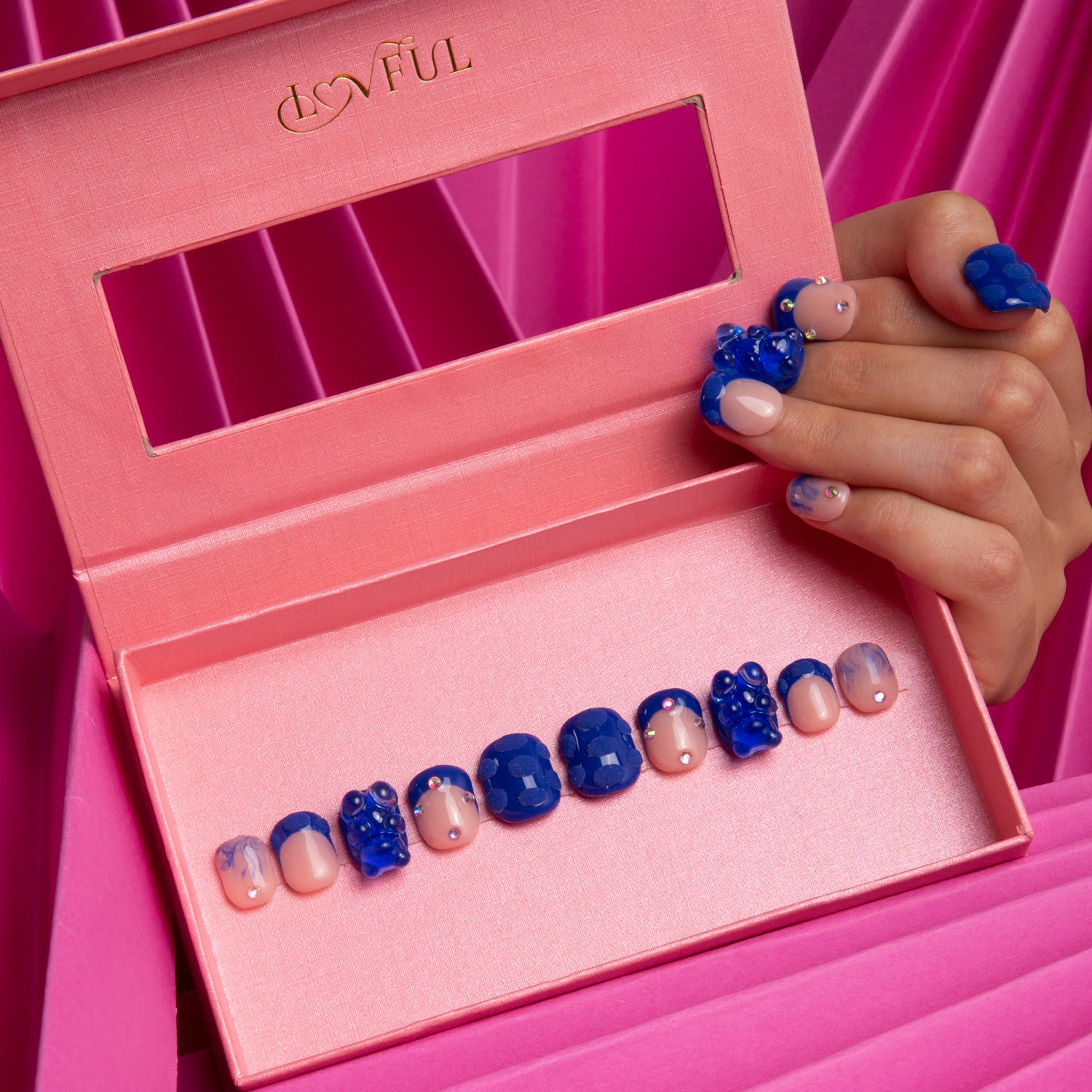 Set of Little Blue Bear press-on square nails in pink box, featuring blue hue with rhinestones, gummy bears, and 3D dots. Hand showing decorated nails.