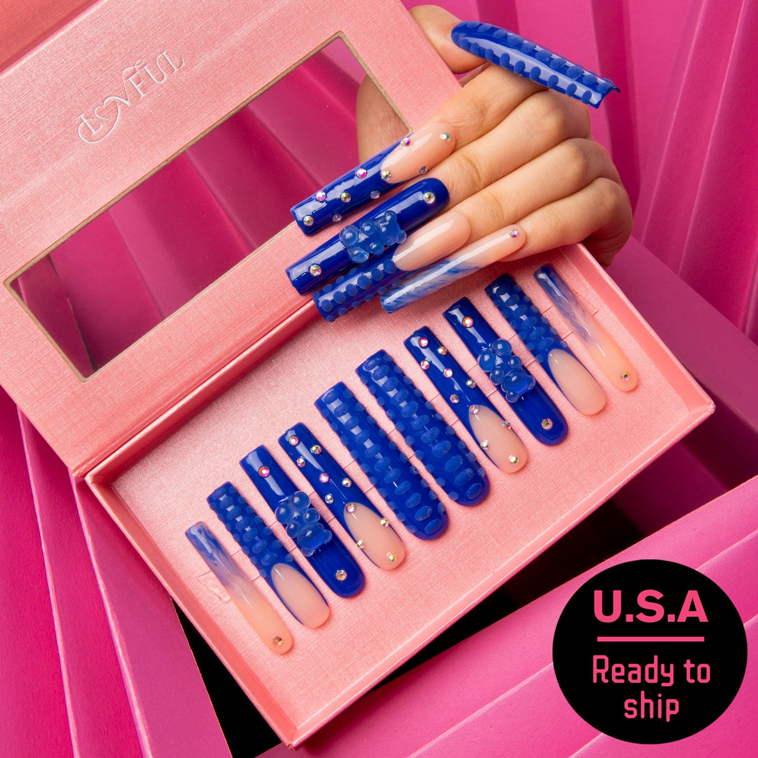Lovful's Little Blue Bear Rhinestone French tip press-on nails in a pink box, featuring blue hue, gummy bears, rhinestones, and 3D dots. A hand holding some nails above the box. Text reads 'U.S.A Ready to ship.'