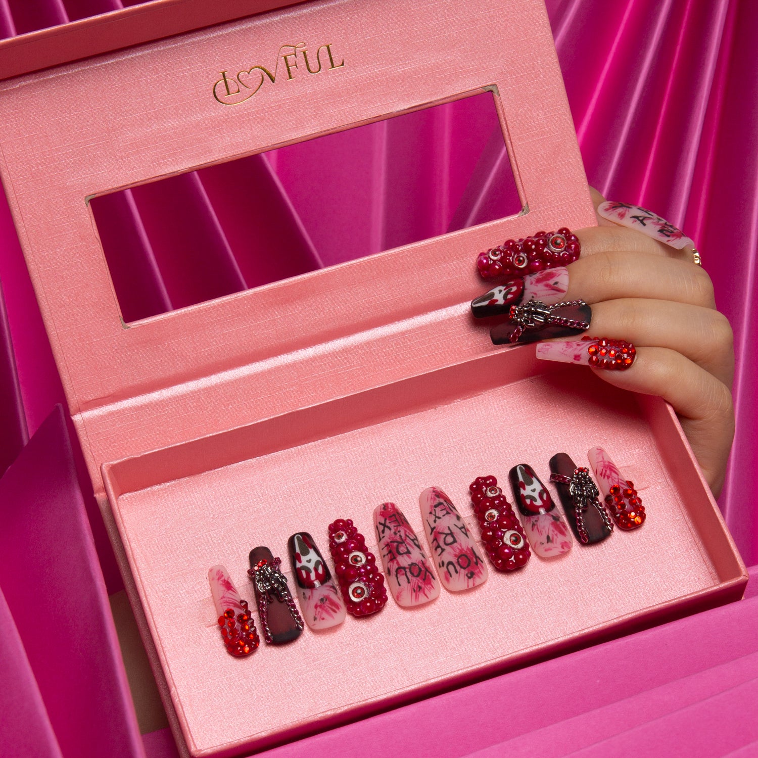 Lovful 'You Are Next' Halloween-themed coffin press-on nails in a pink box, decorated with ghost faces, eerie eyes, and blood-red splashes. Hand with similar nails holding the box.