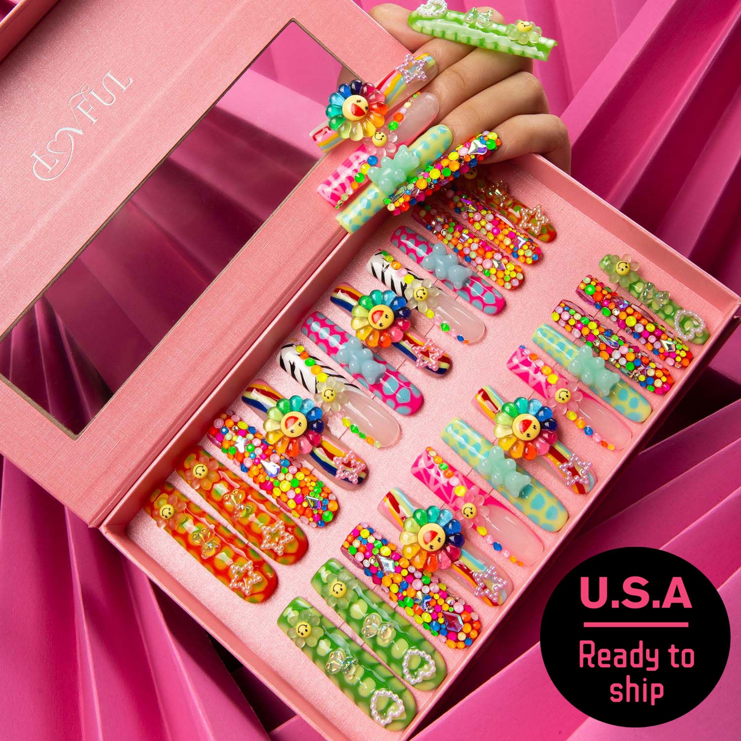 24-piece set of Lovkashi Blossom Press-On Nails featuring colorful sunflower and happy face designs in an open pink box. Hand showcases matching nail designs. Ready to ship from U.S.A.