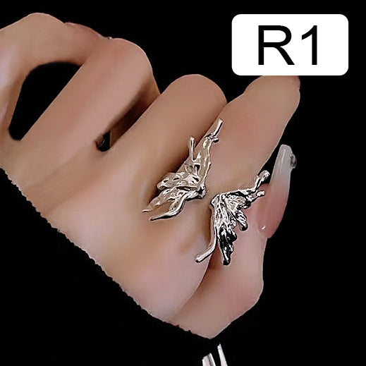 Hand wearing adjustable fashionable metal ring with intricate design labeled 'R1,' partially covered by black sleeve